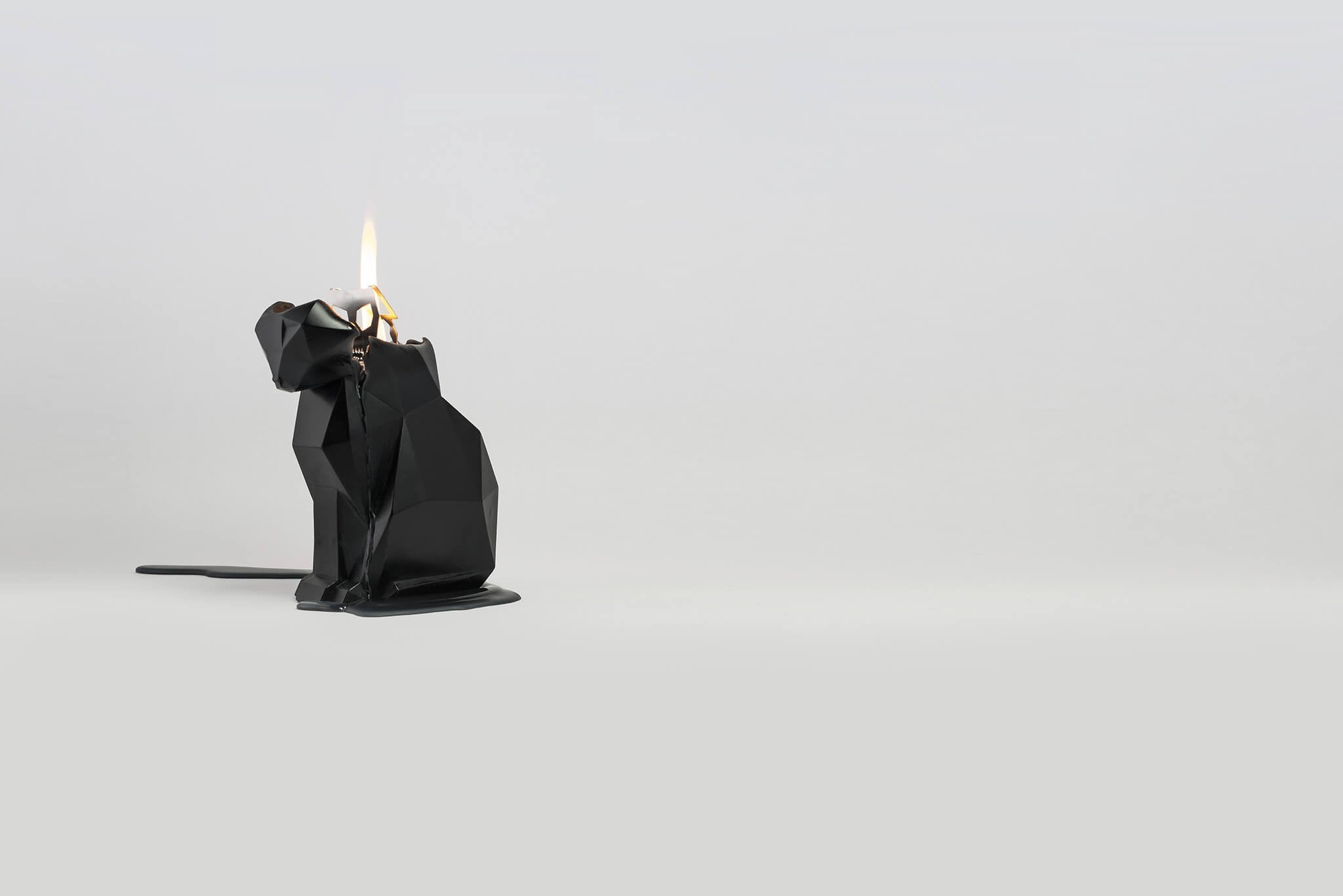 Side view of burning black kisa the cat pyropey candle. Her head is starting to melt. 